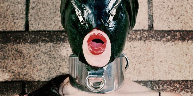 Woman wearing dominatrix outfit with zipper latex mask