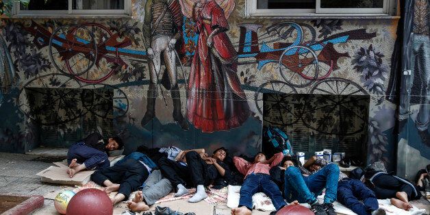 People sleep outside a building near Victoria Square, Athens, where hundreds of migrants and refugees have temporarily camped, on Saturday, Sept. 12, 2015. The European Union will assess the economic costs of the refugee crisis to see whether the nations caught up in it need more lenient budget rules. Greece, Italy and Hungary are among the EU nations hardest hit by the arrival of tens of thousands of migrants this year. (AP Photo/Yorgos Karahalis)