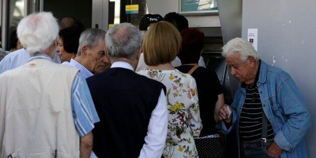A pensioner waits to enter a bank as others stand in a queue to use an ATM of the branch in Athens, Thursday, July 9, 2015. Greece's government is racing to finalize a plan of reforms for its third bailout, hoping this time the proposal will meet with approval from its European partners and stave off a potentially catastrophic exit from Europe's joint currency, the euro, within days. (AP Photo/Thanassis Stavrakis)