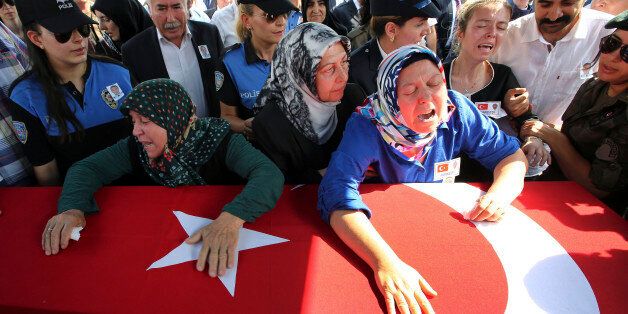 Hulya Aydin, right, the mother of Turkish police special operations officer Sahin Polat Aydin, one of the four officers killed Monday in a landmine attack attributed to militants of the Kurdistan Workers' Party, or PKK, in Silopi, southeastern Turkey, cries over his Turkish flag-draped coffin during a ceremony in Ankara, Tuesday, Aug. 11, 2015. Turkey has seen a sharp spike in clashes between security forces and Kurdish rebels in recent weeks. At least 48 people have died during the renewed vio