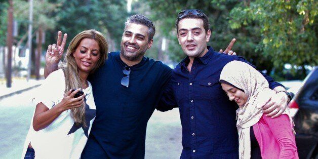 ==EGYPT OUT==Canadian Al-Jazeera journalist Mohamed Fahmy (2L) and his colleague Baher Mohamed (2R) celebrate with their wives Marwa (L) and Jihan (R) after being dropped off by authorities in the upmarket Cairo suburb of Maadi following their release from prison after being pardoned by Egyptian President Abdel Fattah al-Sisi on September 23, 2015. Sisi pardoned the two Al-Jazeera colleagues, along with 100 prisoners, the presidency and official media reported. AFP PHOTO / STR (Photo credit should read STR/AFP/Getty Images)