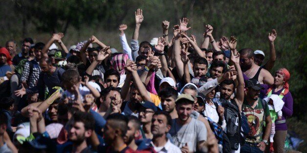 Refugees and migrants raise their hands in order to be allowed by the Macedonian police to cross the border from the northern Greek village of Idomeni to southern Macedonia, Sunday, Sept. 20, 2015. More than 2,000 refugees and economic migrants wait at the small village of about 100 inhabitants every day to be let into Macedonia, from where they continue through Serbia and Hungary to seek asylum in wealthier European countries. (AP Photo/Giannis Papanikos)