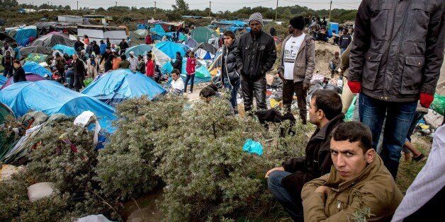 People stand at a site dubbed the 'New Jungle', where some 3,000 people have set up camp -- most seeking desperately to get to England, in Calais on September 21, 2015. The slum-like migrant camp sprung up after the closure of notorious Red Cross camp Sangatte in 2002, which had become overcrowded and prone to violent riots. However migrants and refugees have kept coming and the 'New Jungle' has swelled along with the numbers of those making often deadly attempts to smuggle themselves across the Channel. AFP PHOTO / PHILIPPE HUGUEN (Photo credit should read PHILIPPE HUGUEN/AFP/Getty Images)