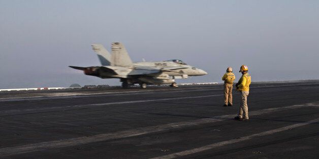 In this Thursday, Sept. 10, 2015 photo, plane directors, wearing yellow jerseys, oversee the takeoff of a U.S. Marine fighter jet aircraft aboard the USS Theodore Roosevelt aircraft carrier. Pilots onboard have flown missions into both Iraq and Syria, part of the over 6,800 airstrikes carried out since August 2014. Some 20 percent of all coalition strikes come from aircraft launched from the nuclear-powered Roosevelt.(AP Photo/Marko Drobnjakovic)
