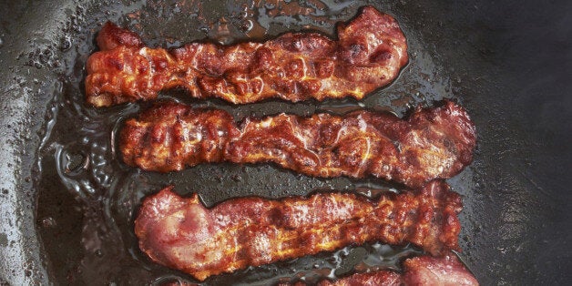 Bacon slice being cooked in frying pan. Close up.