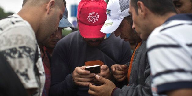 People consult a map on a cell phone as they walk in the direction of Austria, Budapest, Hungary, Saturday, Sept. 5, 2015. Several hundred migrants and refugees started a march from Budapest's Keleti train station towards Austria on Saturday. (AP Photo/Marko Drobnjakovic)