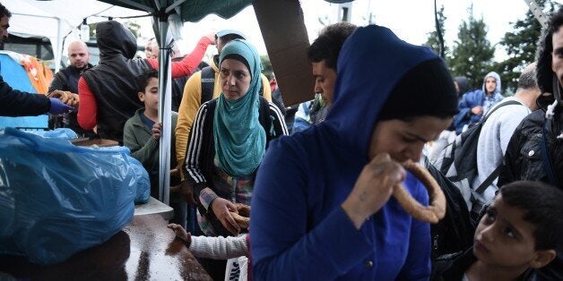 Refugees and migrants queue as police officers hand out milk and bread in the northern Greek village of Idomeni, Monday, Sept. 21, 2015. Hundreds of refugees and economic migrants arrive daily in Idomeni, a small village of some 100 inhabitants, to cross into Macedonia, from where they continue through Serbia and Hungary to seek asylum in wealthier European countries. (AP Photo/Giannis Papanikos)