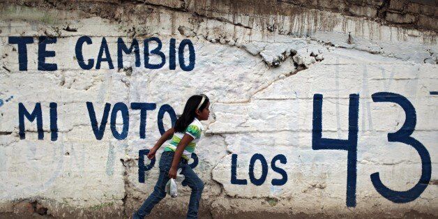 A girl passes by a wall with a graffiti calling to boycot upcoming elections and asking for the 43 missing students in Tlapa de Comonfort, Guerrero State, Mexico on June 4, 2015. Mexicans will vote Sunday for 500 members of the lower chamber of Congress, mayors in nearly 900 municipalities and governors in nine states. Earlier this week, teachers stole and burned thousands of ballots in Oaxaca and Guerrero, but authorities say new ones would be reprinted. AFP PHOTO/ Pedro PARDO (Photo credit should read Pedro PARDO/AFP/Getty Images)