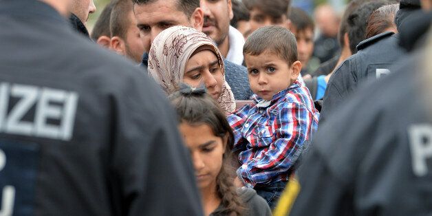 German policemen register refugees at the rail station in Freilassing, Germany, Monday, Sept. 14, 2015, before they take them away in busses. Germany introduced temporary border controls Sunday to stem the tide of thousands of refugees streaming across its frontier, sending a clear message to its European partners that it needs more help with an influx that is straining its ability to cope. (AP Photo/Kerstin Joensson)