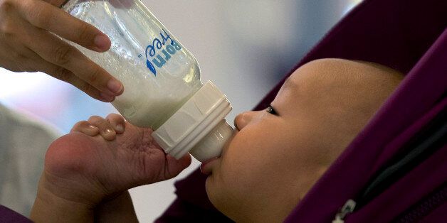 A baby is fed milk from a bottle while sitting in a stroller at a shopping mall in Beijing, China, Wednesday, Aug. 7, 2013. China announced Wednesday it has fined six milk suppliers, including Mead Johnson and New Zealand's Fonterra, a total of $108 million for price-fixing after an investigation that shook the country's fast-growing dairy market. (AP Photo/Andy Wong)