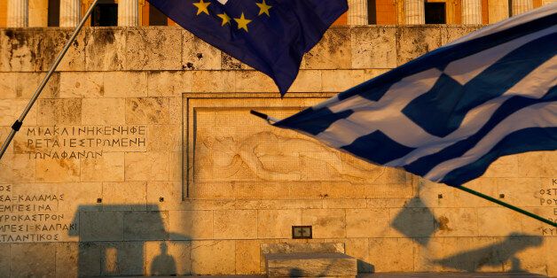 Pro-Euro demonstrators wave a Greek flag, right, and a European Union flag in front of the Tomb of the Unknown Soldier monument during a rally in Syntagma Square in Athens, in this photo dated Thursday, July 9, 2015. The latest incarnation of Greeceâs economic crisis over the span of a month saw Greece in the end accept harsh austerity measures from creditors to save the country from bankruptcy and possibly ignominiously getting kicked out of the eurozone. (AP Photo/Petros Karadjias)