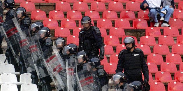 File - In this April 21 2004 photo Gendarmerie officers and soccer fans during a Serbia-Montenegro Cup semi-final soccer match Crvena Zvezda against Partizan, in Belgrade, Serbia. The football hooligans, who are also members of the far-right groups, have played a major role in Serbia over the past 20 years, from taking part in wartime ethnic-cleansing campaigns in Croatian and Bosnia, to helping oust former President Slobodan Milosevic in 2000, protesting against Kosovo's secession, and the most recent street riots against the EU. (AP Photo/Darko Vojinovic, File)