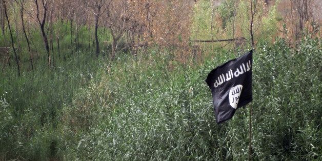 In this image taken Friday, May 29, 2015, a black flag used by the Islamic State group extremists flutters over their combat positions on the front line with Iraqi security forces and allied Shiite militiamen and Sunni tribal fighters on the outside of Ramadi, the capital of Iraq's Anbar province, 70 miles (115 kilometers) west of Baghdad, Iraq. (AP Photo)