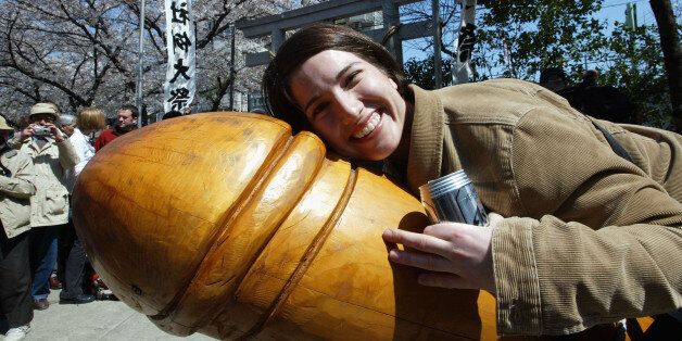 KAWASAKI, JAPAN - APRIL 6: An unidentified woman nestles up to a huge wooden penis April 6, 2003 in Kawasaki, Japan. People of all ages participate in the annual Penis Festival or Kanamara Matsuri (Festival of the Steel Phallus) held at the Wakamiya Hachimangu Shrine, which promotes safe sex and AIDS awareness. (Photo by Koichi Kamoshida/Getty Images)