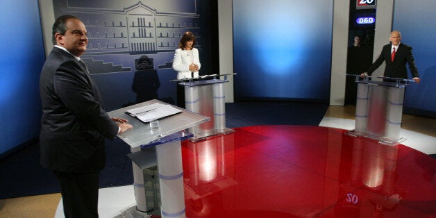 Greek Prime Minister Costas Karamanlis, left, and Greece's opposition Socialists leader George Papandreou, far right, look on as a Greek television journalist Maria Houkli checks her papers before a debate in Athens on Tuesday, Sept. 22, 2009. Greece's opposition Socialists have retained a strong lead in the last opinion polls published before the Oct. 4 general election. Three nationwide surveys published in newspapers Friday give George Papandreou's Socialists a lead of between 6 and 7 points over Prime Minister Costas Karamanlis' conservatives all projecting the main opposition party will win enough seats in parliament to form the next government. (AP Photo/Thanassis Stavrakis)