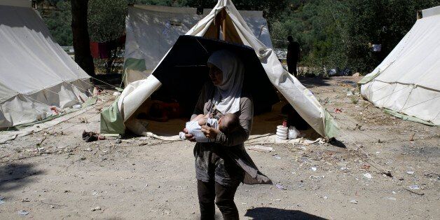A Syrian mother holds her ten month-old son Ahmad after their arrival at a refugee and migrant camp in the village of Moria on the northeastern Greek island of Lesvos on Wednesday, June 17, 2015. The Aegean island has borne the brunt of a huge influx of migrants from the Middle East, Asia and Africa crossing from Turkey to nearby Greek islands. More than 50,000 migrants have arrived in Greece so far this year. (AP Photo/Thanassis Stavrakis)