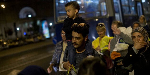 People walk as they attempt to board buses provided by Hungarian authorities for migrants and refugees at Keleti train station in Budapest, Hungary, Saturday, Sept. 5, 2015. Hundreds of migrants boarded buses provided by Hungary's government as Austria in the early-morning hours said it and Germany would let them in. Austrian Chancellor Werner Faymann announced the decision early Saturday after speaking with Angela Merkel, his German counterpart - not long after Hungary's surprise nighttime move to provide buses for the weary travelers from Syria, Iraq and Afghanistan. (AP Photo/Marko Drobnjakovic)