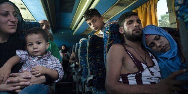 Refugees fleeing the war in Syria sit on a bus as they are driven to the Kokkinotrimithia refugee camp, West of Nicosia in Cyprus, on September 6, 2015 a few hours after they were rescued as their boat ran into trouble overnight off the Mediterranean island. The 114 people, including 54 women and children, had been aboard a small fishing boat about 40 nautical miles from the southern Cypriot port of Larnaca at the time they struck trouble, said a source in the island's Joint Rescue Coordination Centre. The boat was mainly carrying Syrian refugees, but also some Lebanese and Palestinians from Syria. AFP PHOTO / IAKOVOS HATZISTAVROU (Photo credit should read IAKOVOS HATZISTAVROU/AFP/Getty Images)