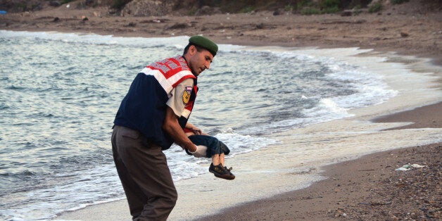 A paramilitary police officer carries the lifeless body of a migrant child after a number of migrants died and a smaller number were reported missing after boats carrying them to the Greek island of Kos capsized, near the Turkish resort of Bodrum early Wednesday, Sept. 2, 2015. (AP Photo/DHA) TURKEY OUT