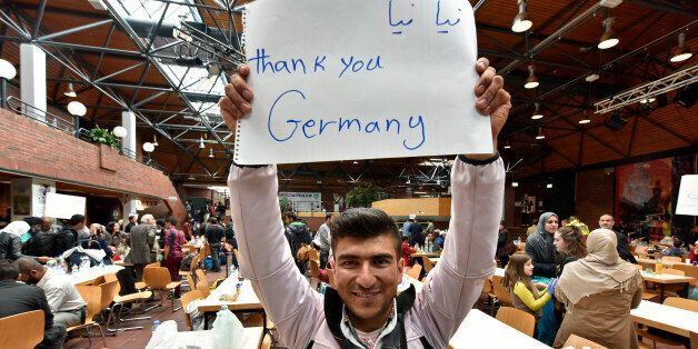 A refugee from Afghanistan holds a banner reading 'Thank you Germany' at a hall in Dortmund, Germany, Sunday, Sept. 6, 2015. Thousands of migrants and refugees arrived in Dortmund by trains. (AP Photo/Martin Meissner)