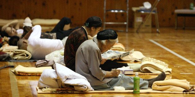 SAYO, JAPAN - AUGUST 10: (JAPANESE NEWSPAPERS OUT) Evacuated people read newspapers at Sayo Kinrosha Taiiku Center after Typhoon Etau on August 10, 2009 in Sayo, Hyogo, Japan. At least thirteen people were killed and eighteen are still missing following floods and landslides after Typhoon Etau hit Western Japan. (Photo by Sankei/Getty Images)