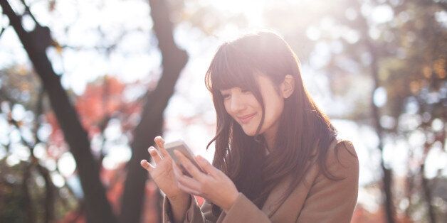Woman feels happiness with using smartphone in a nature.