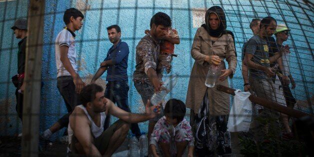 Refugees take water from a hose at the port of Mitylene on the northeast Greek island of Lesbos while waiting to board a ferry traveling to Athens, on Tuesday, Sept. 8, 2015. The island of some 100,000 residents has been transformed by the sudden new population of some 20,000 refugees and migrants, mostly from Syria, Iraq and Afghanistan. (AP Photo/Santi Palacios)