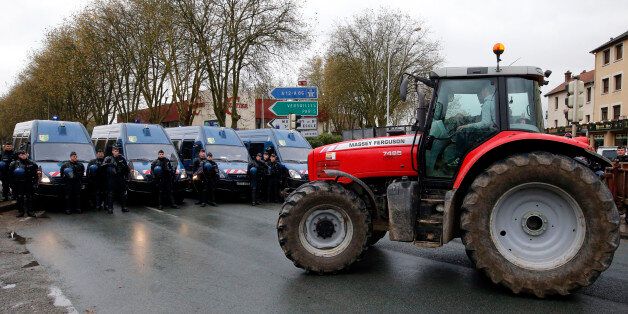 A French farmer in his tractor faces French riot gendarmery on a secondary road converging on Paris slowing traffic to a crawl in the second low speed protest in Trappes, west of Paris, Thursday Nov. 21, 2013. The French president's popularity edges lower by the week, dragged down by a sluggish economy that is eroding people faith and their willingness to pay some of the highest taxes. (AP Photo/Francois Mori)