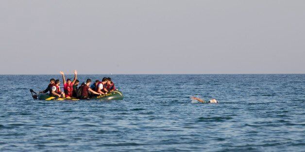 Migrants and refugees, one of them swims, arrive after crossing from Turkey, at the southeastern island of Kos, Greece, Monday, Aug. 17, 2015. With the lights of the Greek island of Kos twinkling through the darkness, beacons of hope for a new and better life, another group of migrants has come through this wealthy tourist town to make a risky, but less risky than most, sea crossing and apply for asylum in Europe. (AP Photo/Alexander Zemlianichenko)