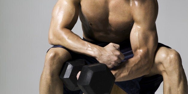 medium shot of a male bodybuilder as he lifts a weight