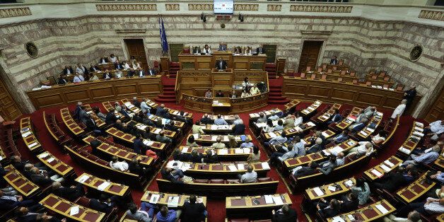 Lawmakers take part in a parliamentary session in Athens, Friday, Aug. 14, 2015. Greek lawmakers are continuing a debate in parliament to approve a massive new bailout deal after repeated delays over procedure and dissent within the governing left-wing Syriza party caused the session to last through the night. (AP Photo/Yannis Liakos)