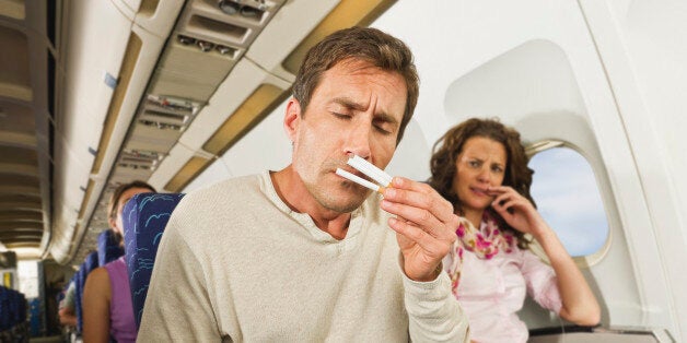 Germany, Munich, Bavaria, Man smelling cigarettes and women getting annoyed in economy class airliner