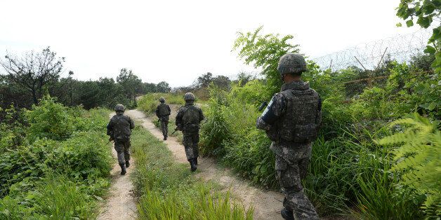 In this Aug. 9, 2015, photo provided by the Defense Ministry, South Korean army soldiers patrol near the scene of a blast inside the demilitarized zone in Paju, South Korea. Vowing to hit back, South Korea said Monday, Aug. 10, 2015, that North Korean soldiers laid the three mines that exploded last week at the border and maimed two South Korean soldiers. (The Defense Ministry via AP)