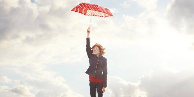 Young woman flying with umbrella.