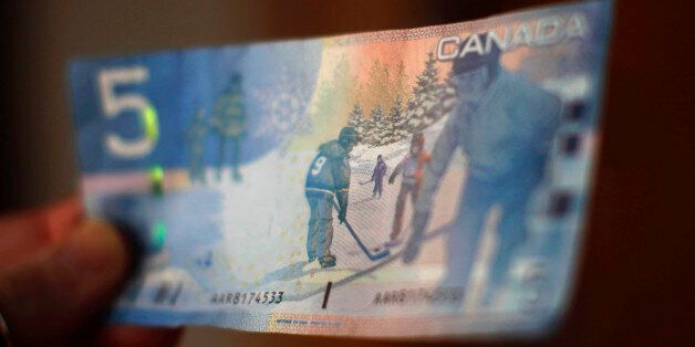 A Canadian five-dollar bill is seen in this posed photograph in Montreal March 10, 2011. The National Hockey League was under attack from all sides on Thursday as fans, sponsors and politicians expressed outrage at the rising levels of violence in the sport, following a devastating hit on Montreal Canadiens' forward Max Pacioretty. The romantic image of children playing hockey on a pond that appears on Canada's five-dollar bill was replaced by disturbing pictures of Pacioretty lying unconscious on the ice on Tuesday after having his head violently slammed into partition at the end of the players' bench by the Boston Bruins' hulking 6-foot, 9-inch, 260-pound defenseman Zdeno Chara. REUTERS/Shaun Best (CANADA - Tags: SPORT ICE HOCKEY BUSINESS)