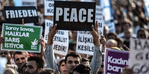 People hold placards reading 'peace' in different languages during a peace gathering in Istanbul on August 9, 2015. Nearly 400 members of the outlawed Kurdistan Workers' Party (PKK) have been killed and hundreds injured in two weeks of Turkish airstrikes on positions in northern Iraq, the official Anatolia news agency reported. Turkey last month launched a two-pronged 'anti-terror' offensive against Islamic State (IS) jihadists in Syria and PKK militants after a wave of attacks inside the country. But so far the Kurdish rebels have borne the brunt of dozens of airstrikes, while just three have been officially recognised as targeting IS. AFP PHOTO / OZAN KOSE (Photo credit should read OZAN KOSE/AFP/Getty Images)