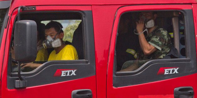 Chinese firefighters wear masks as they wait in their truck near the site of an explosion in northeastern China's Tianjin municipality Saturday, Aug. 15, 2015. State media reported that the casualties of the first three squads of firefighters to respond and of a neighborhood police station have not yet been determined, suggesting that the death toll could still go up. (AP Photo/Ng Han Guan)