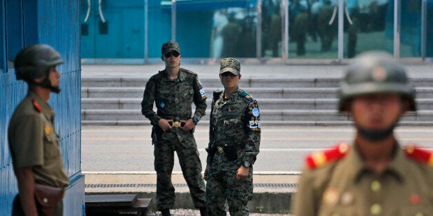 South Korean soldiers inspect as their North Korean counterparts stand guard during a reunification rally in the border village of Panmunjom at the DMZ in North Korea, Saturday, Aug. 15, 2015. Though staged to mark the 70th anniversary of Japanese World War II defeat, the rally came just after Pyongyang said the south had committed an act of war by broadcasting anti-North Korea propaganda across the border. (AP Photo/Dita Alangkara)