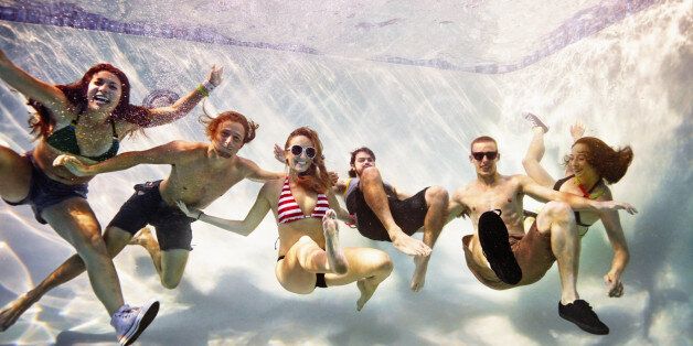 Smiling group of friends embracing underwater view from underwater