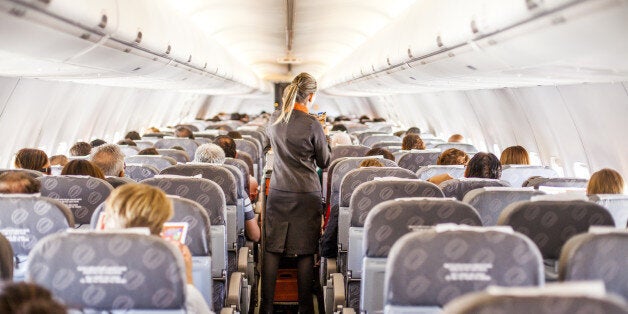 A scene from the inside of a airplane with passengers and attendants working.