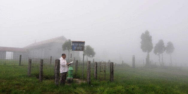 TO GO WITH India-climate-travel-nature-rain-Guinness,FEATURE by Ammu KannampillyIn this photograph taken on June 21, 2013, Indian technician, Ramkrishna Sharma, 53, in-charge of the rain measuring looks at his log book at Mawsynram village in the north-eastern Indian state of Meghalaya and considered the 'wettest place on earth' according to the Guinness World Records authority. Deep in India's northeast, villagers use grass to sound-proof their huts from deafening rain, clouds are a familiar si