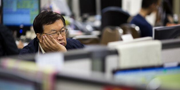A stockbroker sits in front of a screen displaying share prices at a securities brokerage in Hong Kong, China, on Monday, Aug. 24, 2015. Hong Kong's snowballing stock losses are, by one measure, the most extreme since the crash of 1987. Photographer: Jerome Favre/Bloomberg via Getty Images