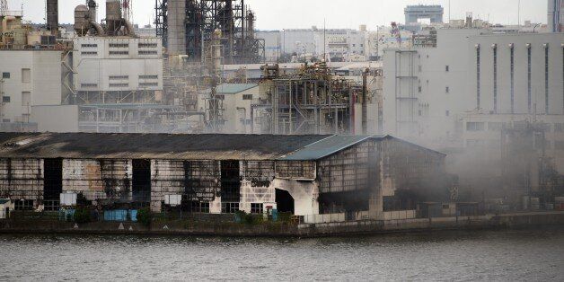 Smoke rises from a steel plant beside a river in Kawasaki near Tokyo's Haneda airport on August 24, 2015. A huge blaze broke out August 24 in a steel plant near Tokyo's Haneda airport, a fire department official said, as television images showed plumes of thick black smoke and flames shooting up into the air. AFP PHOTO / TOSHIFUMI KITAMURA (Photo credit should read TOSHIFUMI KITAMURA/AFP/Getty Images)
