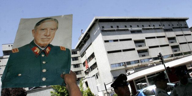 A supporter of former Gen. Augusto Pinochet raises a portrait of him in front of the Military Hospital in Santiago, Chile, Tuesday, Dec. 5, 2006. Pinochet's condition is no longer life threatening, doctors said Tuesday, but said he would remain in the hospital for at least 10 days. The 91-year-old former dictator suffered an acute heart attack Sunday and was rushed to the Military Hospital where priests administered his last rites. (AP Photo/ Claudio Santana)