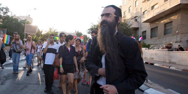 Ultra-Orthodox Jew Yishai Schlissel walks through a Gay Pride parade and is just about to pull a knife from under his coat and start stabbing people in Jerusalem, Thursday, July 30, 2015. Schlissel was recently released from prison after serving a term for stabbing several people at a gay pride parade in 2005, a police spokeswoman said.(AP Photo/Sebastian Scheiner)