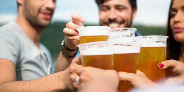 Group of friends toasting with beer in plastic glasses