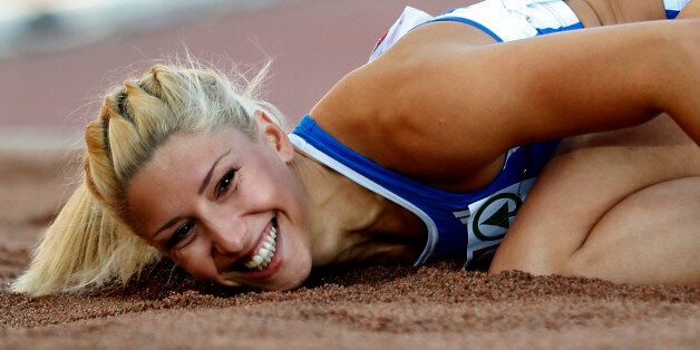 FILE- Greece's Voula Papachristou lands in the sand after her jump at the Women's Triple Jump final at the European Athletics Championships in Helsinki, Finland, in this file photo dated Friday, June 29, 2012. The Hellenic Olympic Committee has removed triple jumper Voula Papachristou from the team taking part in the upcoming London Olympic Games over comments she made on twitter making fun of African immigrants and expressing support for a far-right party. âThe track and field athlete Paraskevi (Voula) Papachristou is placed outside the Olympic Team for statements contrary to the values and ideas of the Olympic movement,â a statement by the Hellenic Olympic Committee says. Papachristou is in Athens, and was to travel to London âshortly before the track events start,â the announcement says.(AP Photo/Matt Dunham, file)