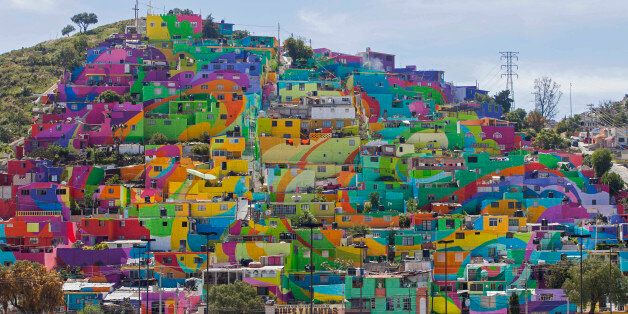 In this Thursday, July 30, 2015 photo, hundreds of houses painted in bright colors in what organizers claim is Mexico's largest mural, is part of a government-sponsored project is called Pachuca Paints Itself, in the Palmitas neighborhood, in Pachuca, Mexico. German Crew is the artist collective responsible for painting the mural project. Director Enrique Gomez, who goes by MYBE, said the crew has painted 1,500 square meters with 20,000 liters of paint. The project aims to bring the community together and rehabilitate the area. (AP Photo/Sofia Jaramillo)