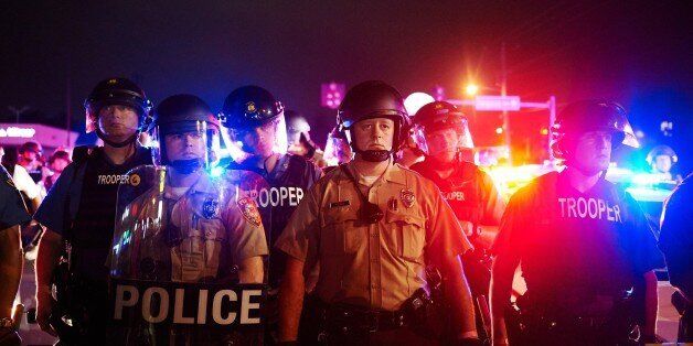 St. Louis County Police and Missouri State Highway Patrol troopers stand guard as protesters march on West Florissant Avenue in Ferguson, Missouri on August 9, 2015. A day of peaceful remembrance marking the anniversary of 18-year-old black teen Michael Brown's killing by police in the US city of Ferguson came to a violent end on August 9 as gunfire left at least one protester injured. AFP PHOTO / MICHAEL B. THOMAS (Photo credit should read Michael B. Thomas/AFP/Getty Images)