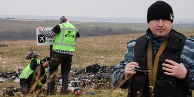 Pro-Russian rebel fighter guard an area of the Malaysia Airlines Flight 17 plane crash in the village of Hrabove, Donetsk region, eastern Ukraine Tuesday, Nov. 11, 2014, as MH17 flight recovery team members erect a